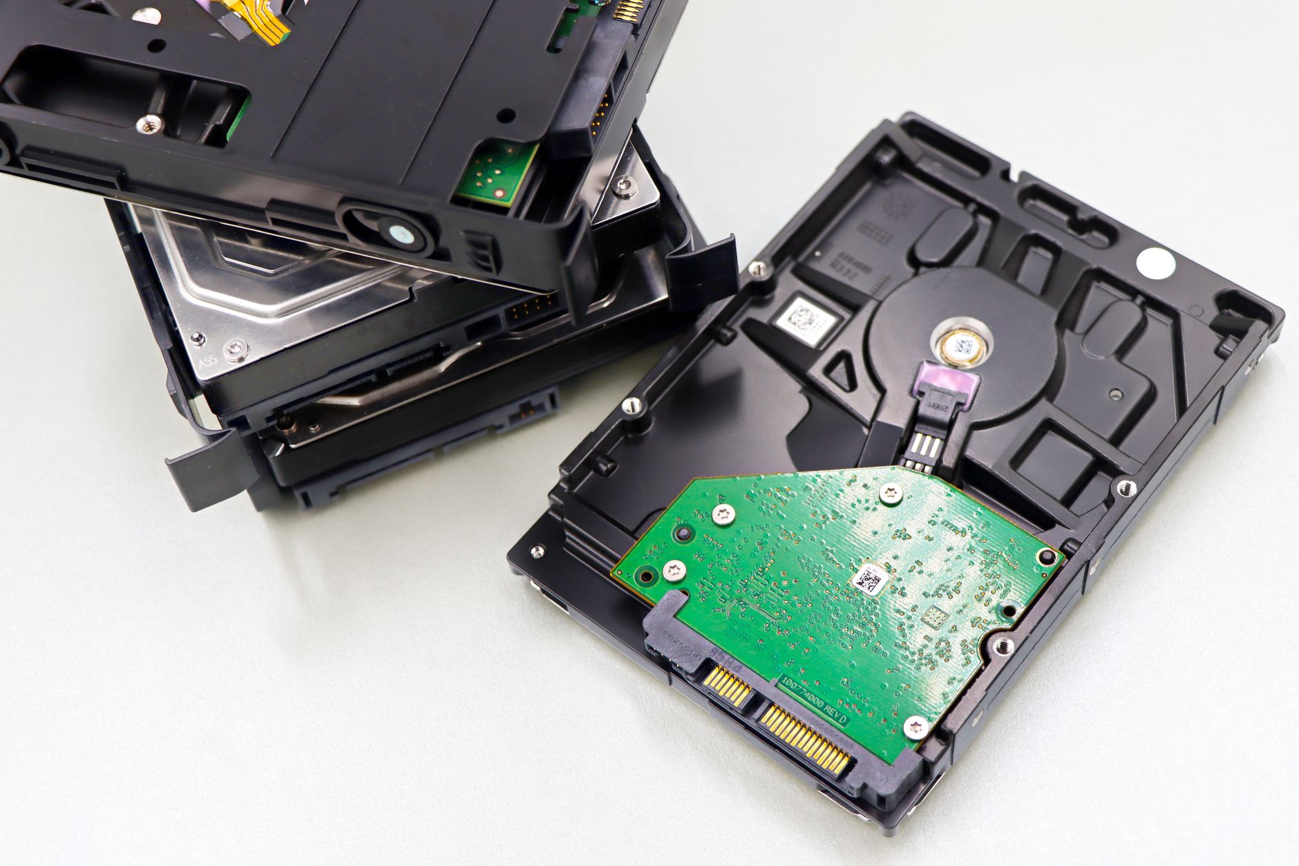 A collection of dismantled hard disk drives displayed on a white surface, showcasing internal components.